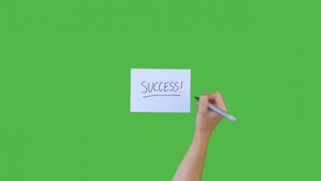Woman-Writing-Success!-on-Paper-with-Green-Screen