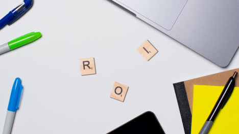 Stop-Motion-Business-Concept-Above-Desk-Wooden-Letter-Tiles-Forming-Acronym-ROI