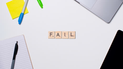 Stop-Motion-Business-Concept-Above-Desk-Wooden-Letter-Tiles-Forming-Word-Fail