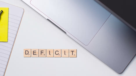 Stop-Motion-Business-Concept-Above-Desk-Wooden-Letter-Tiles-Forming-Word-Deficit-1