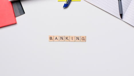 Stop-Motion-Business-Concept-Above-Desk-Wooden-Letter-Tiles-Forming-Word-Banking
