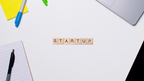 Stop-Motion-Business-Concept-Above-Desk-Wooden-Letter-Tiles-Forming-Word-Startup