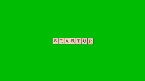 Stop-Motion-Business-Concept-Overhead-Wooden-Letter-Tiles-Forming-Word-Startup-On-Green-Screen