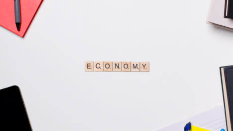 Stop-Motion-Business-Concept-Above-Desk-Wooden-Letter-Tiles-Forming-Word-Economy