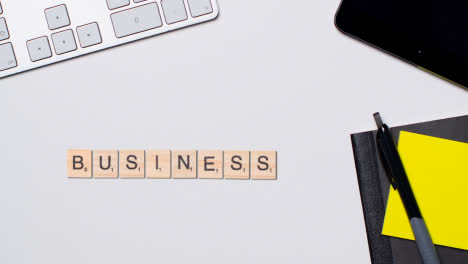 Stop-Motion-Business-Concept-Above-Desk-Wooden-Letter-Tiles-Forming-Word-Business-1