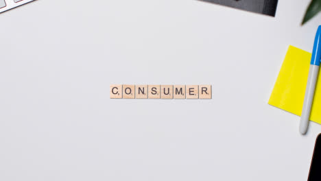 Stop-Motion-Geschäftskonzept-über-Dem-Schreibtisch-Aus-Holzbuchstabenfliesen,-Die-Das-Wort-Verbraucher-Bilden