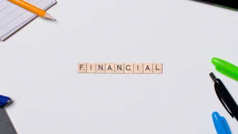 Stop-Motion-Business-Concept-Above-Desk-Wooden-Letter-Tiles-Forming-Word-Financial