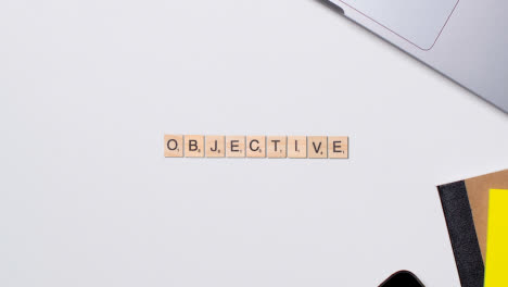 Stop-Motion-Business-Concept-Above-Desk-Wooden-Letter-Tiles-Forming-Word-Objective