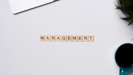 Stop-Motion-Business-Concept-Above-Desk-Wooden-Letter-Tiles-Forming-Word-Management