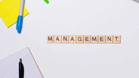 Stop-Motion-Business-Concept-Above-Desk-Wooden-Letter-Tiles-Forming-Word-Management-1