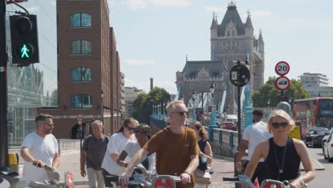 Turistas-De-Verano-Caminando-Y-En-Bicicleta-Por-El-Puente-De-La-Torre-De-Londres,-Inglaterra,-Reino-Unido-Con-Tráfico
