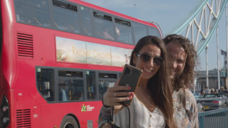 Tourist-Couple-Taking-Selfie-On-Visit-To-Tower-Bridge-London-England-UK