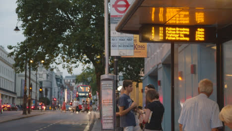 Pasajeros-Que-Esperan-En-La-Parada-Del-Busto-En-Una-Carretera-Muy-Transitada-En-Londres,-Inglaterra,-Reino-Unido