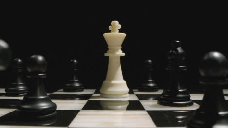 Studio-Shot-Of-Chess-Board-With-White-King-Surrounded-By-Opponents-Black-Pieces-1