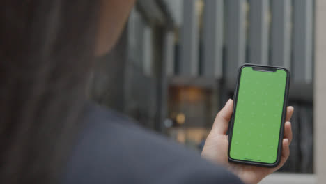 Businesswoman-Outside-City-Of-London-Offices-Holding-Green-Screen-Mobile-Phone