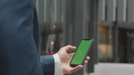 Businessman-Outside-City-Of-London-Offices-Holding-Green-Screen-Mobile-Phone-1