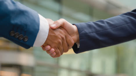 Close-Up-Of-Businesswoman-And-Businessman-Meeting-And-Shaking-Hands-Outside-Office-London-City-Office