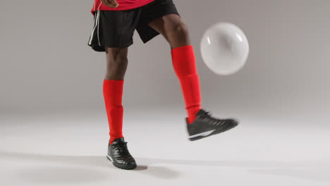 Close-Up-Of-Male-Footballer-In-Studio-Playing-Keepy-Uppy-Kicking-Ball