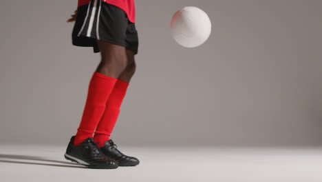 Close-Up-Of-Male-Footballer-In-Studio-Playing-Keepy-Uppy-Kicking-Ball-3