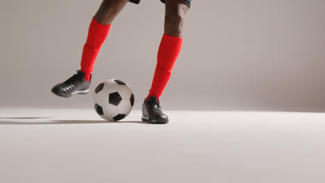 Close-Up-Of-Male-Footballer-In-Studio-Controlling-And-Flicking-Ball-Into-The-Air-