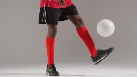 Close-Up-Of-Male-Footballer-In-Studio-Playing-Keepy-Uppy-Kicking-Ball-4
