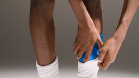Studio-Close-Up-Of-Male-Footballer-Or-Sportsperson-Putting-Shin-Guards-Into-Socks