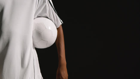 Close-Up-Of-Male-Footballer-In-Studio-With-Ball-Under-Arm