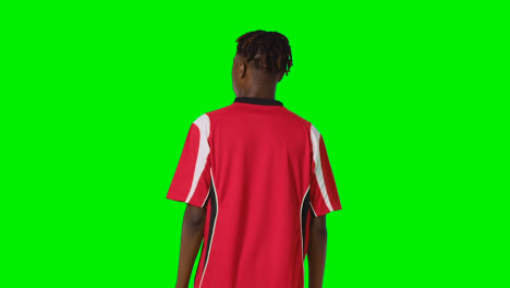 Rear-View-Of-Young-Male-Footballer-Wearing-Club-Kit-Watching-Game-Against-Green-Screen