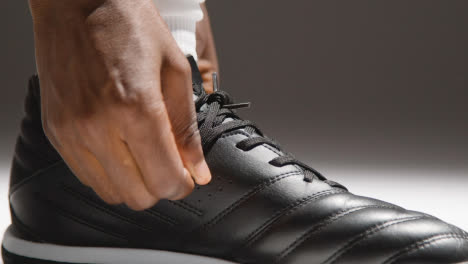 Studio-Close-Up-Of-Male-Footballer-Or-Sportsperson-Tying-Laces-On-Boots-Or-Training-Shoes-2