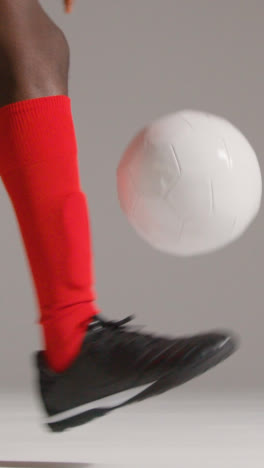 Vertical-Video-Close-Up-Studio-Shot-Of-Male-Footballer-In-Studio-Playing-Keepy-Uppy-Kicking-Ball-1