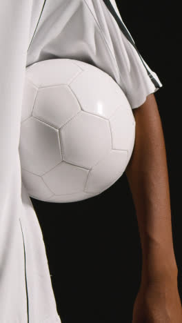 Vertical-Video-Close-Up-Of-Male-Footballer-In-Studio-With-Ball-Under-Arm