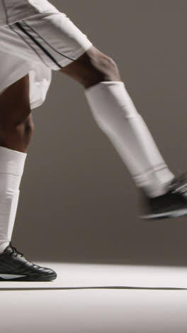 Vertical-Video-Close-Up-Of-Male-Footballer-Wearing-Club-Kit-Kicking-Or-Passing-Ball