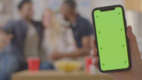 Friends-Celebrating-Watching-Sports-Game-On-TV-At-Home-With-Green-Screen-Mobile-Phone-In-Foreground-2