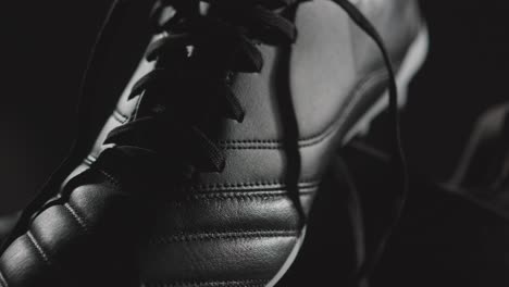 Studio-Still-Life-Shot-Of-Football-Soccer-Boots-Revolving-Against-Black-Background