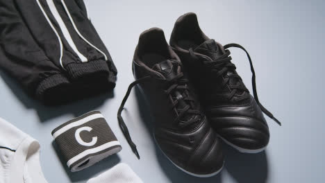 Studio-Still-Life-Shot-Of-Football-Soccer-Boots-Ball-Shirt-And-Shorts-And-Captains-Armband-