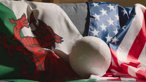 Sofa-In-Der-Lounge-Mit-Amerikanischen-Und-Walisischen-Flaggen-Und-Ball,-Während-Sich-Die-Fans-Darauf-Vorbereiten,-Fußballspiele-Im-Fernsehen-1-Zu-Sehen