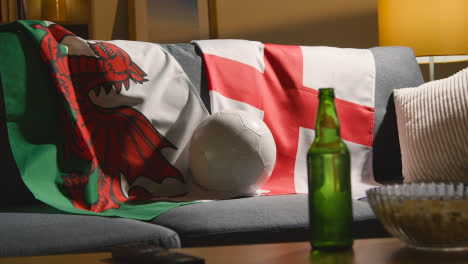 Sofa-In-Lounge-With-English-And-Welsh-Flags-And-Ball-As-Fans-Watch-Football-Soccer-Match-On-TV-2