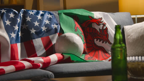 Sofa-In-Lounge-With-Welsh-And-American-Flags-And-Ball-As-Fans-Watch-Football-Soccer-Match-On-TV-2