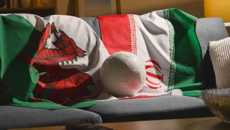 Sofa-In-Lounge-With-Welsh-And-Iranian-Flags-And-Ball-As-Fans-Prepare-To-Watch-Football-Soccer-Match-On-TV-4