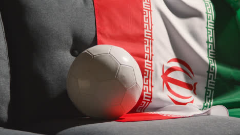 Sofa-In-Der-Lounge-Mit-Iranischer-Flagge-Und-Ball,-Während-Sich-Die-Fans-Darauf-Vorbereiten,-Fußballspiele-Im-Fernsehen-Zu-Sehen-3