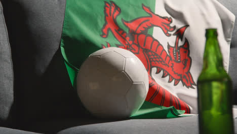 Sofa-In-Lounge-With-Welsh-Flag-And-Ball-As-Fans-Prepare-To-Watch-Football-Soccer-Match-On-TV-