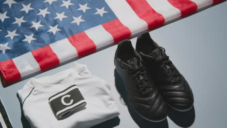 Studio-Still-Life-Shot-Of-Football-Soccer-Boots-American-Flag-Shirt-And-Shorts-And-Captains-Armband-