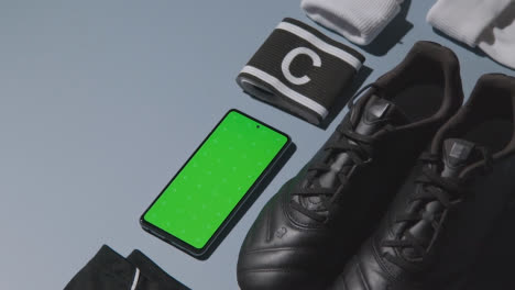 Studio-Flat-Lay-Shot-Of-Football-Soccer-Boots-Shorts-Captains-Armband-And-Mobile-Phone