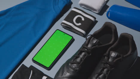 Studio-Flat-Lay-Shot-Of-Football-Soccer-Boots-Shirt-Captains-Armband-Shin-Guards-And-Mobile-Phone-1