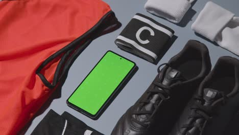 Studio-Flat-Lay-Shot-Of-Football-Soccer-Boots-Training-Bib-Captains-Armband-And-Mobile-Phone-2