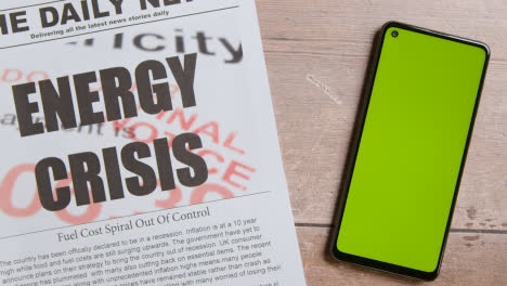 Zeitung-Mit-Schlagzeile-Zur-Energiekrise-Neben-Greenscreen-Handy-Mit-Handscrolling