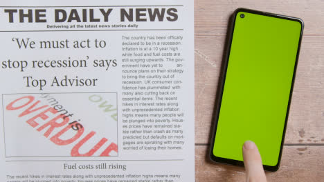 Newspaper-With-Headline-On-Recession-Next-To-Green-Screen-Mobile-Phone-With-Hand-Scrolling-1