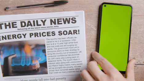 Zeitung-Mit-Schlagzeile-Zur-Energiepreiskrise-Neben-Der-Hand,-Die-Das-Greenscreen-Handy-Ablegt