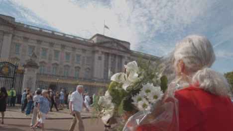 Primer-Plano-De-Un-Doliente-Sosteniendo-Flores-Fuera-Del-Palacio-De-Buckingham