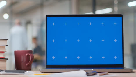 Blue-Screen-Laptop-on-Desk-In-Hospital-With-Medical-Staff-In-Background